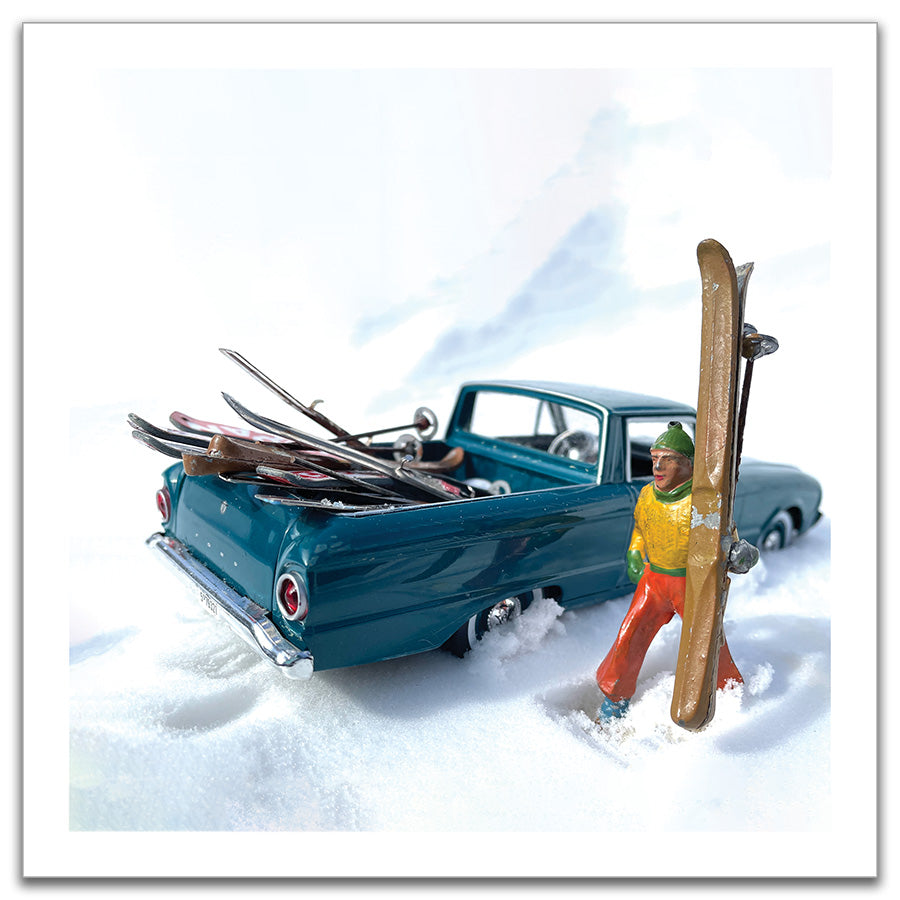 Print of a vintage toy skier holding skies near a truck